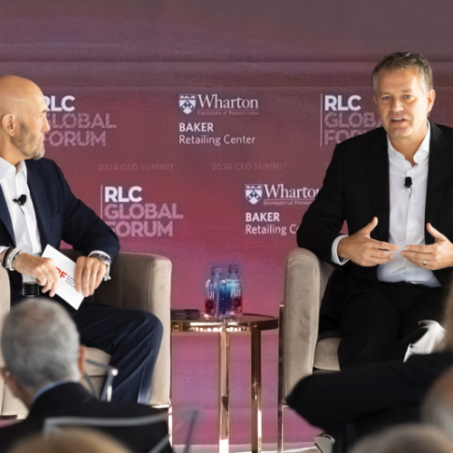 Two people seated on stage at the RLC Global Forum, part of the Wharton Baker Retailing Center's 2024 CEO Summit, engaged in a discussion.