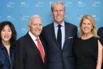 A small group of people dressed formally, standing in front of a blue backdrop featuring logos for the Wharton Baker Retailing Center and RLC Global Forum.